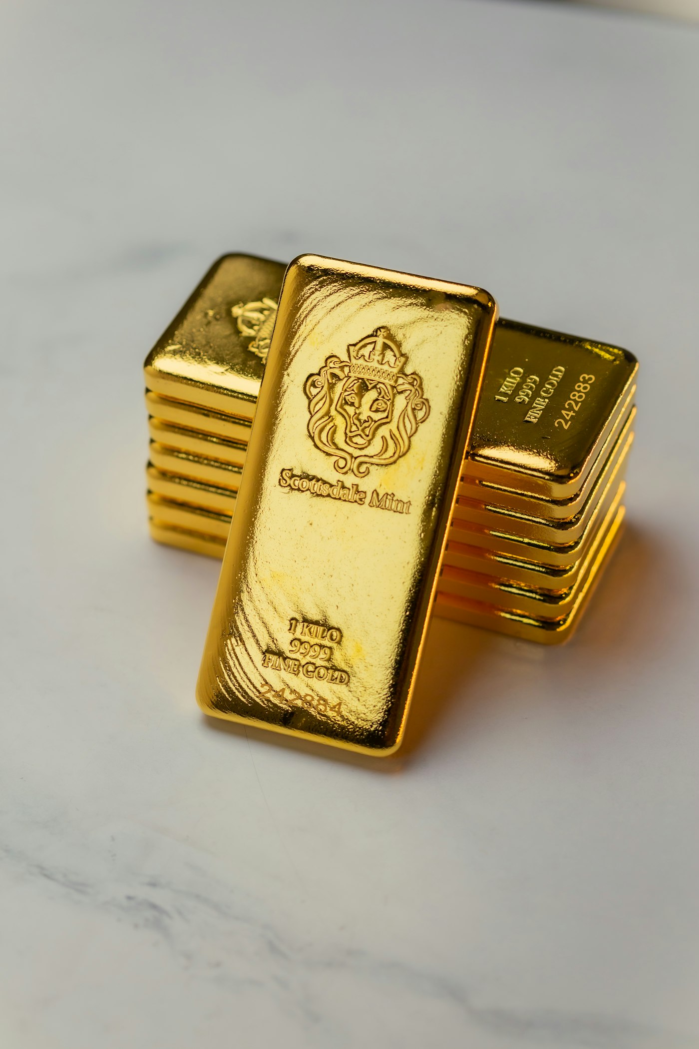 Goldbarren aus 9999 Feingold liegen gestapelt auf einer dunklen Unterlage